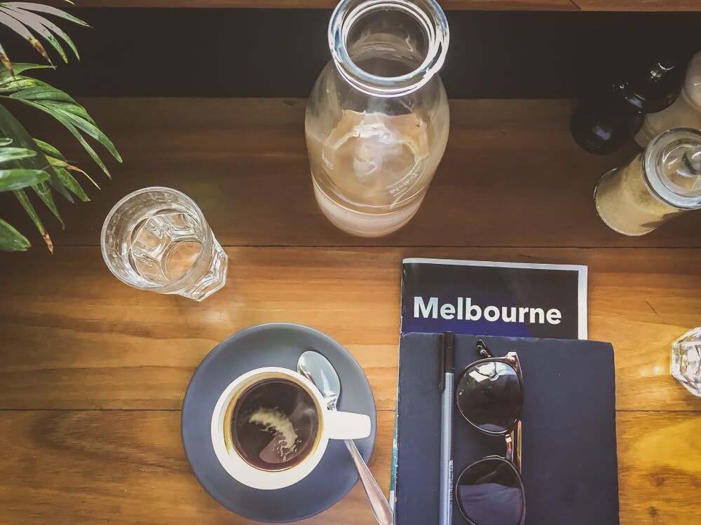 Coffee in a cafe with a Melbourne tourist brochure and sunglasses