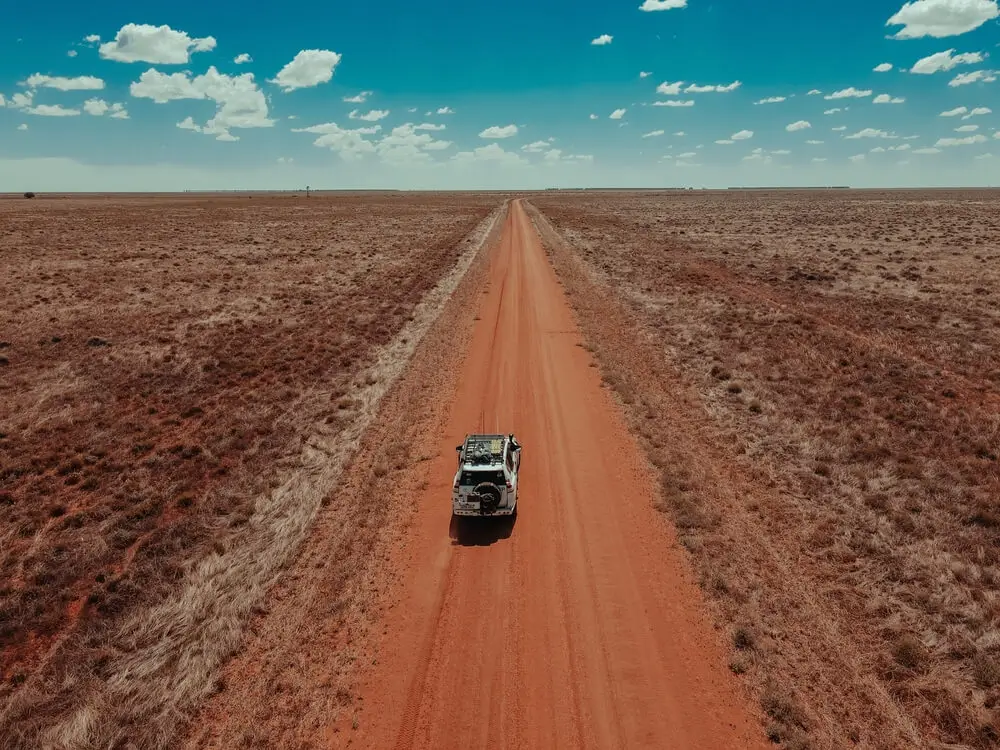 Car driving through the red desert of the Outback